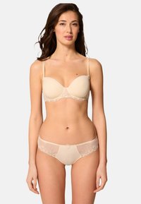 Beige alusvaatteet, jotka sisältävät topatun rintaliivin ja siihen sopivat alushousut. Rintaliivissä on pitsikoristuksia, ja alushousuissa on brodeerattuja yksityiskohtia.