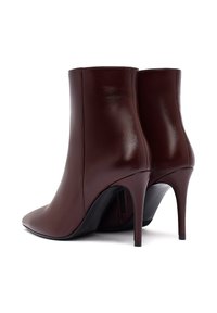 Bruine leren enkellaarsjes met een spitse neus en hoge stilettohak. Glad oppervlak, geen zichtbare patronen, discrete rits aan de zijkant.