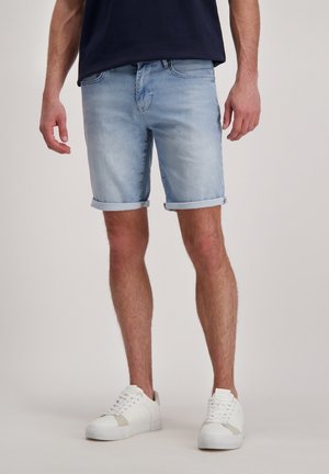 Lichtblauwe denim shorts met opgerolde zoom, voorzien van een klassieke vijf-pocketontwerp en een rits, gecombineerd met witte sneakers.