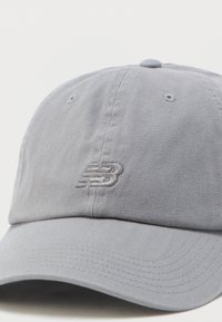 Ανοιχτό γκρι καπέλο μπέιζμπολ με ραμμένες οπές αερισμού και διακριτικό κεντημένο λογότυπο "NB" στο κέντρο της μπροστινής πλευράς.
