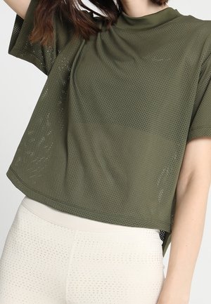 Top de malla verde oliva de mangas cortas con un cuello alto, que presenta un corte holgado y hombros caídos, combinado con leggings texturizados en un beige claro.