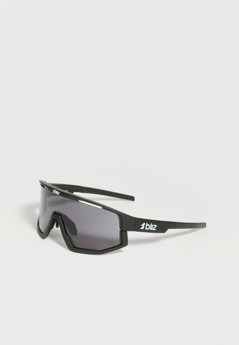 Μαύρα αθλητικά γυαλιά ηλίου με γωνιώδεις σκούρους φακούς και λευκό λογότυπο "Bliz" στο πλάι, εμφανιζόμενα σε ανοιχτό γκρι φόντο.