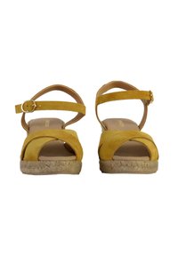 Yellow suede espadrille sandals with crossed straps, a buckle ankle closure, and a jute-wrapped wedge heel.