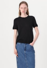 Svart kortärmad T-shirt i ett mjukt och lätt material. Enkel rundhalsad design i kombination med en högmidjad jeanskjol.
