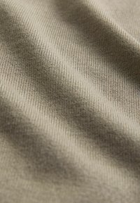 Světlý taupe textil s jemnou žebrovanou strukturou, která předvádí měkké, hladké linie a jemný lesk, zvýrazňuje jeho tkaný vzor.