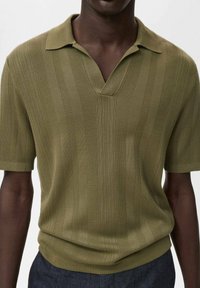 Olivgrünes, gestricktes Poloshirt mit V-Ausschnitt, vertikalen Streifen und kurzen Ärmeln. Hergestellt aus weichem Stoff mit strukturierten Akzenten.