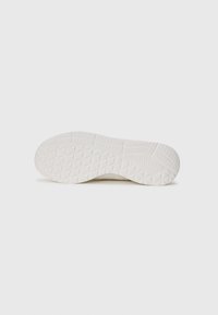 White sneaker sole featuring a textured rubber surface with a diamond pattern for traction and smooth edges. Minimalistic design.
