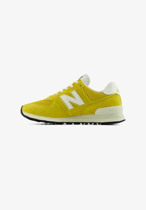 Baskets athlétiques jaunes et blanches avec lacets blancs, empeigne en mesh et semelle noire texturée, montrées de profil sur fond blanc.