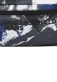 Sort-hvid mulepose med blå abstrakte mønstre. Har tekstureret materiale og præget logo "KARL LAGERFELD JEANS" i sort.