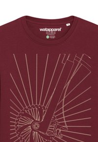 Bordeaux t-shirt met een lijntekening ontwerp van een fietswiel en vork, met uitstralende lijnen in een lichte kleur, wat een dynamisch visueel effect creëert.