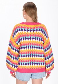 Pulover din croșetat cu un model colorat în diamante, în nuanțe de roz, galben, mov și albastru, având o silueta largă și manșete întărite.