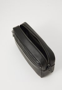 Black leather toiletry bag with textured surface, two zippered compartments, and silver hardware. Upright rectangular shape. Smooth accents.