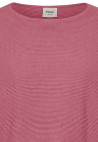 Gros plan sur le col d'un pull en maille rose poudré avec une étiquette de marque blanche « fransa » cousue à l'intérieur du col.