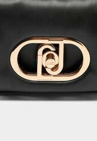 Sort læderhåndtaske med en guldfarvet oval spænde med sammenflettet design og mærkenavnet "LIU JO" indgraveret.