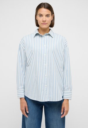 Jasnoniebieska koszula w paski z długimi rękawami, zapięciami na guziki i zaokrąglonym dołem. Tkanina ma gładką fakturę i pionowe paski o różnych szerokościach.