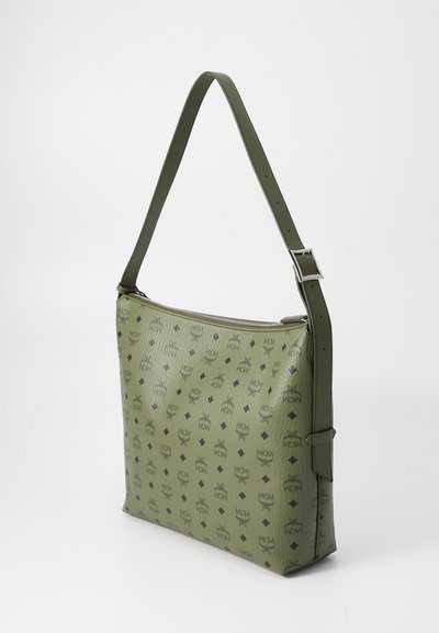 Olive green leather shoulder bag with adjustable strap, zipper closure, and black MCM logo pattern across its surface.