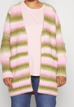 Personne portant un cardigan rayé ouvert à l'avant avec des bandes horizontales rose, verte et blanche sur une chemise rose pâle et un jean bleu.