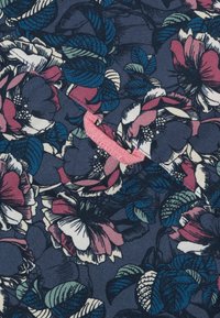 Bloemstof met grote roze en witte bloemen en groene bladeren op een donkerblauwe achtergrond; bevat een klein detail in het rood.