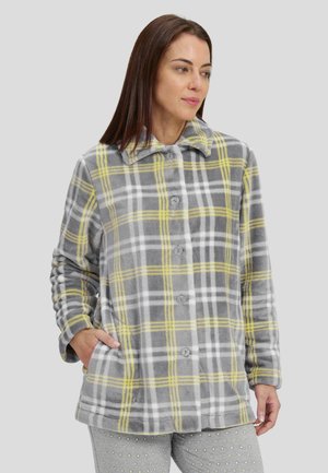 Chaqueta de forro polar a cuadros grises con acentos amarillos, que presenta un cierre de botones, cuello y bolsillos laterales, combinada con pantalones estampados.
