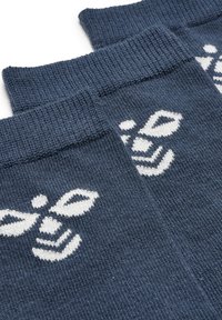 Marinblå strumpor med ett vitt bivmönster, ribbad mudd och en slät stickad yta. Mönstret är vävt i tyget.