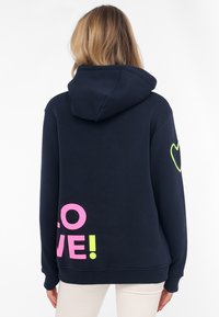 Felpa blu navy con una grande grafica "LOVE!" rosa e verde sul retro e un cuore verde sulla manica destra. Realizzata in tessuto morbido.