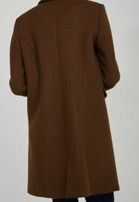Cappotto in misto lana marrone con finitura testurizzata, caratterizzato da un taglio dritto e senza chiusure visibili. Spalle sagomate e dettagli sulle cuciture laterali.