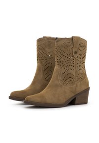 Botines de ante marrón con diseños recortados, punteras afiladas y tacones apilados. La costura en contraste añade detalle a la silueta de la bota.