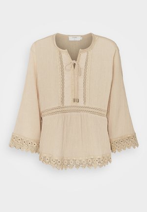 Beżowa bluzka z długim rękawem z koronkową lamówką na mankietach i dole, pionowymi koronkowymi panelami oraz wiązaniem na okrągłym dekolcie.