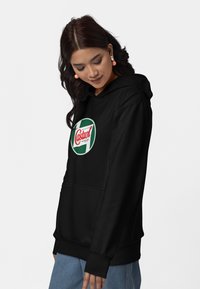 Felpa nera realizzata in tessuto morbido, con tasca frontale e un logo circolare "Castrol" in verde e rosso. Maniche lunghe con polsini a costine.