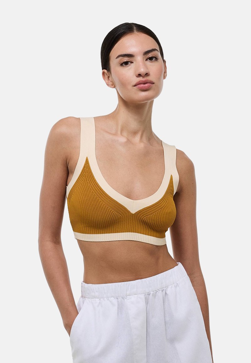 Soutien-gorge de sport marron et crème à côtes avec un décolleté en V et des bretelles larges, présentant un motif texturé le long du buste.