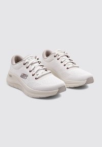Zapatillas deportivas blancas con parte superior de malla transpirable, cierre de cordones y suela acolchada. Presenta sutiles acentos beige en el talón y la lengüeta.