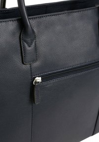 Marineblauwe leren handtas met een gestructureerde afwerking, voorzien van twee handvatten en een ritsvak aan de voorkant met zilverkleurige hardware.