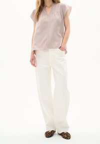 Blusa rosa chiaro a maniche corte con scollo a V e pieghe, abbinata a pantaloni bianchi a vita alta con gamba larga e ballerine con stampa leopardata.