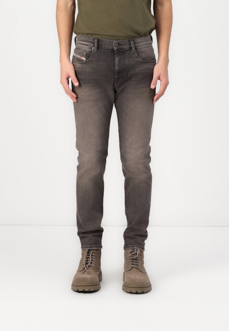 Jeans din denim gri cu o croială slim, având un finisaj decolorat, cinci buzunare și cusături contrastante, asortați cu bocanci din suede maro.