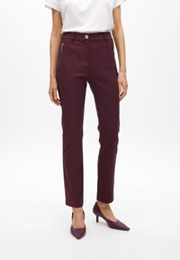 Pantalones de corte entallado en burdeos, con detalles de cremallera en los bolsillos, cierre de botón y una textura de tela suave.