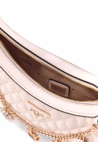 Borsa a tracolla trapuntata rosa con hardware dorato, dotata di una tracolla a catena e etichetta interna. La chiusura con zip rivela un rivestimento liscio.