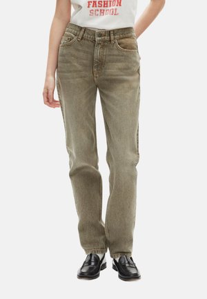 Light green denim jeans with a straight fit, five pockets, and copper stitching. Worn with black loafers and a white graphic t-shirt.