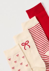 Drei Paar Socken: ein Paar in einfarbigem Rot, ein Paar in Creme mit roten Schleifenmustern und ein gestreiftes Paar in Creme und Rot, alle mit gerippten Bündchen.