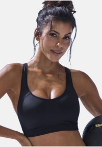 Top corto sportivo nero realizzato in tessuto traspirante, con spalline larghe e scollatura a barca, dalla texture liscia e design aderente.