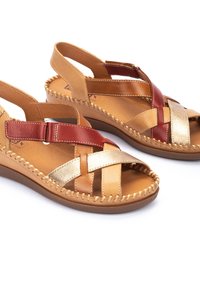 Sandalias de cuero trenzado con tiras rojas, doradas y marrones, con una plantilla acolchada y una suela de cuña baja con un acento de costura.