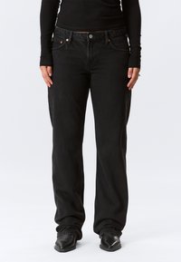 Jeans in denim nero con una vestibilità rilassata, design a cinque tasche e dettagli in metallo. Il materiale testurizzato offre una resistenza durevole.