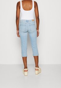 Vaaleansiniset lyhyet farkut, joissa on napakka muotoilu. Viiden taskun tyyli, jossa on pieni ruskea logo takana vyötäröllä. Yhdistetty vaaleanbeigeihin korkokenkiin.