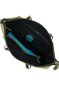 Interno di una borsa in pelle verde con fodera nera, caratterizzato da una tasca con accento blu e un'etichetta con marchio. Chiusura con zip e hardware in tono argento.