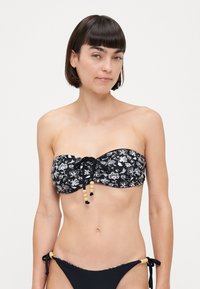 Μαύρο μπικίνι τοπ χωρίς τιράντες με λευκό λουλουδάτο σχέδιο; διαθέτει λεπτομέρεια με κορδόνι διακοσμημένο με ξύλινες χάντρες; συνδυάζεται με μαύρο μπικίνι σλιπ.