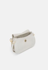 Grå læder crossbody taske med gyldent hardware, en magnetisk knaplukning og et blødt, struktureret interiør. Har et rent, minimalistisk design.