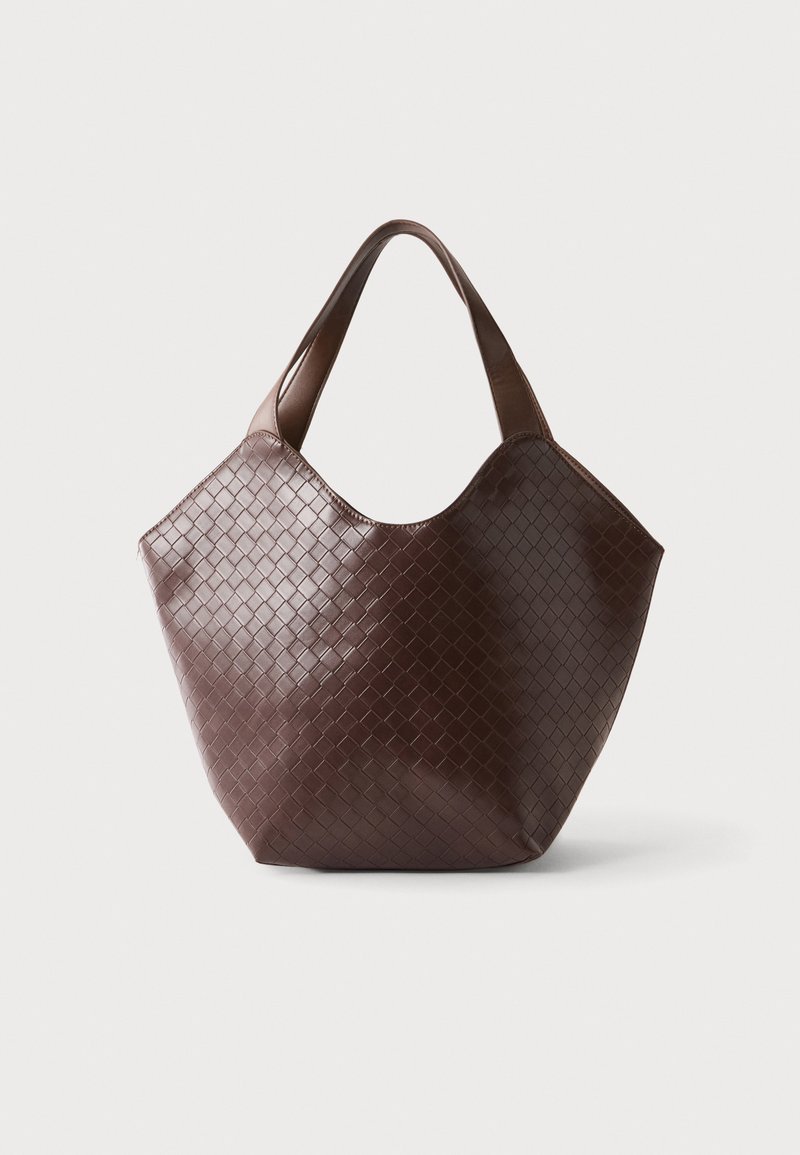 Sac à bandoulière en cuir tressé marron foncé avec de larges anses et une forme trapézoïdale large sur un fond uni.
