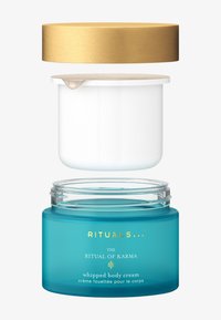 En genomskinlig turkos burk med ett guldmetallock visar en vit kräm inuti. Texten på burken inkluderar "RITUALS", "RITUAL OF KARMA" och "vispad kroppskräm."