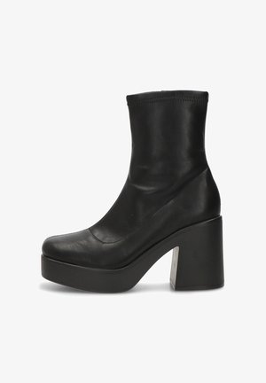 Botín de cuero negro que presenta una silueta elegante, punta redondeada y un tacón alto y grueso con un acento texturizado en la base del tacón.