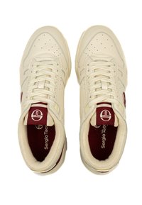 Beige ādas sporta apavi ar sarkanu iekšpusi un logo, tiem ir perforēti detaļas, plakani šņores un strukturēts dizains.