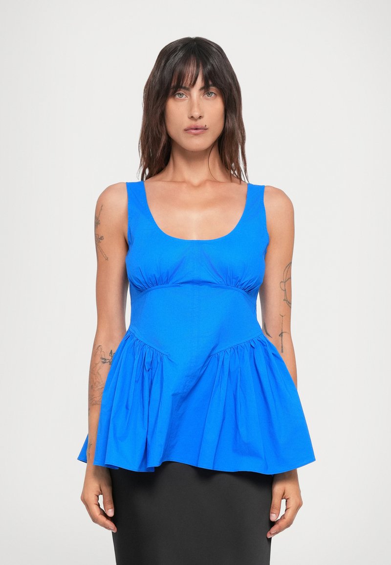 Blue peplum top with a scoop neckline, gathered fabric at the waist, and a flared hem. Made of smooth cotton with no visible hardware.